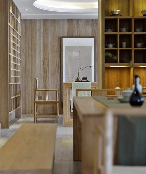 Layered view through pale timber furniture toward a quiet tea setting