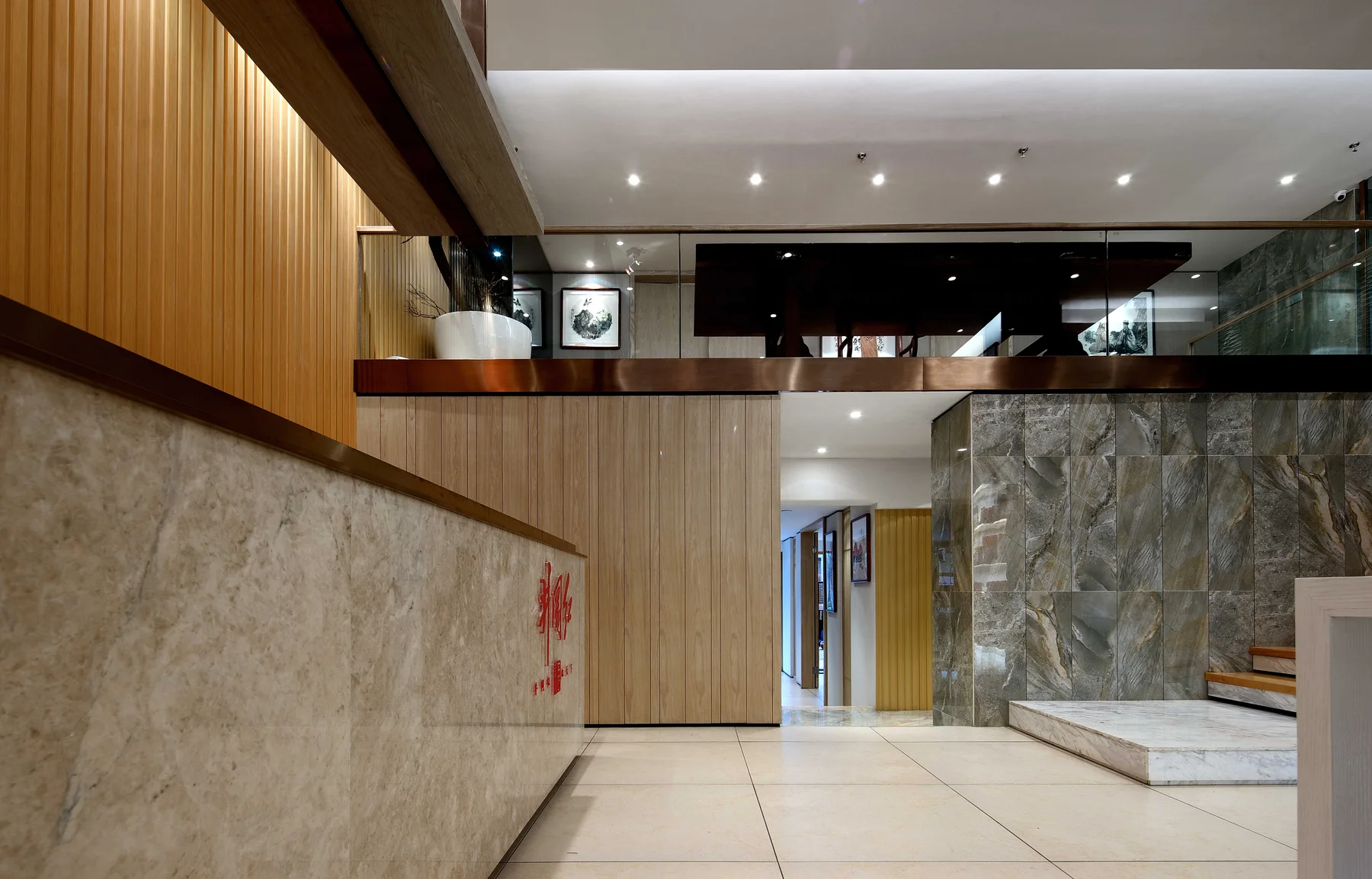 Layered reception counter linking the timber lobby to the marble stair