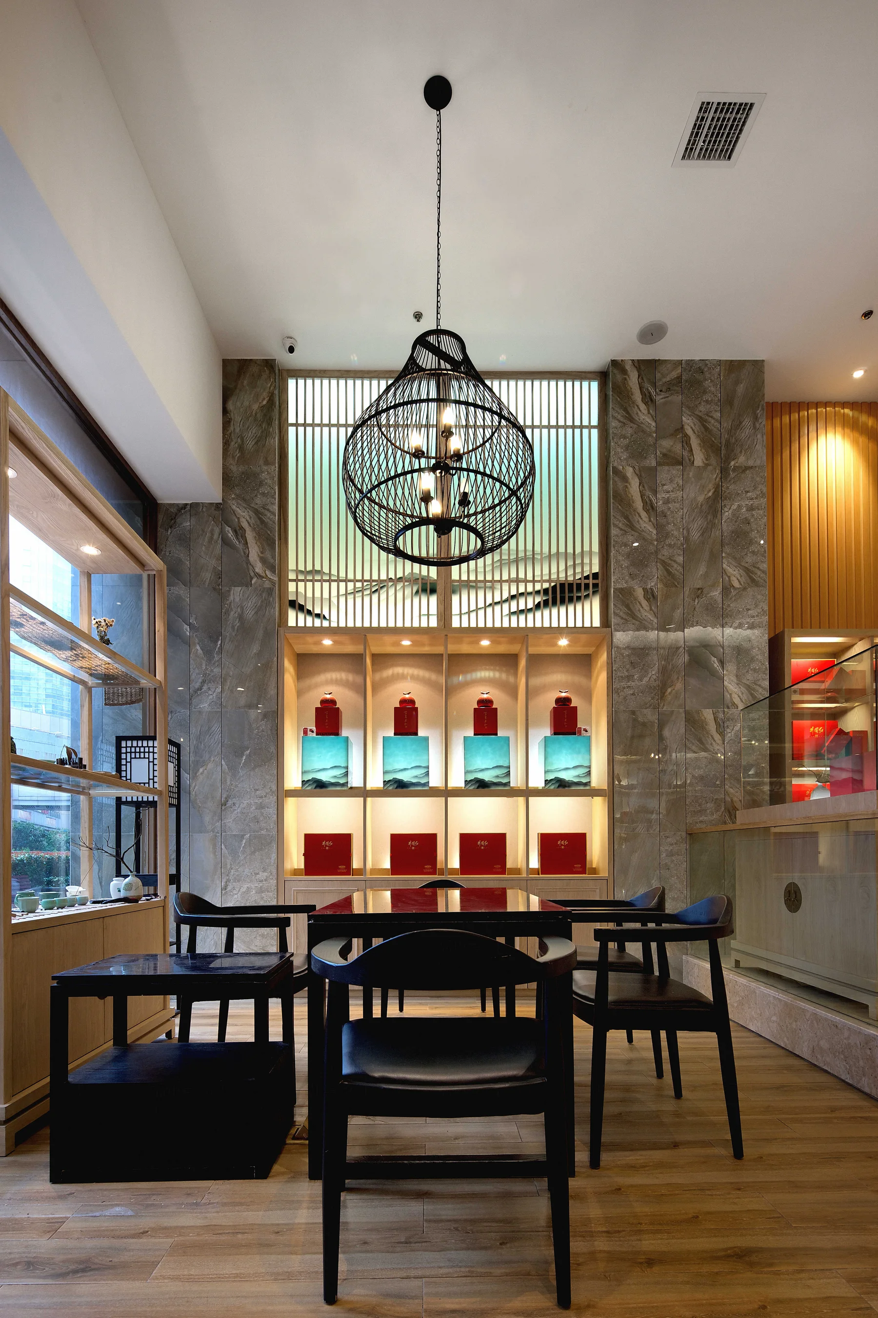 Intimate tea table beneath a woven pendant and backlit product niches